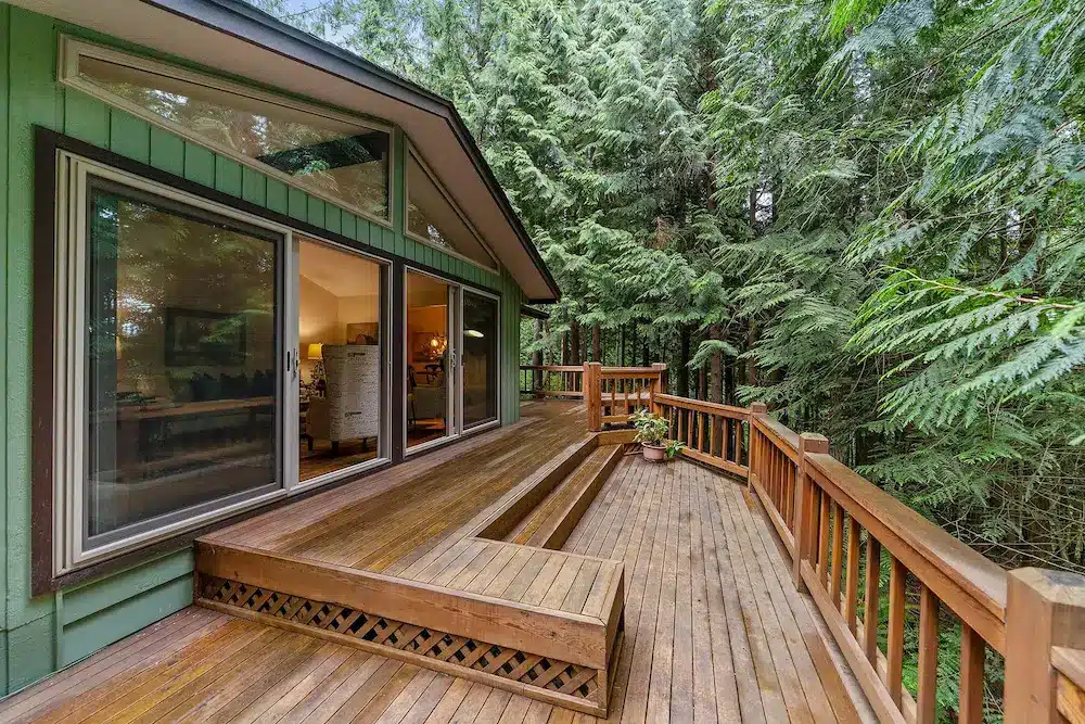 Custom deck on green house in lush green wooded setting