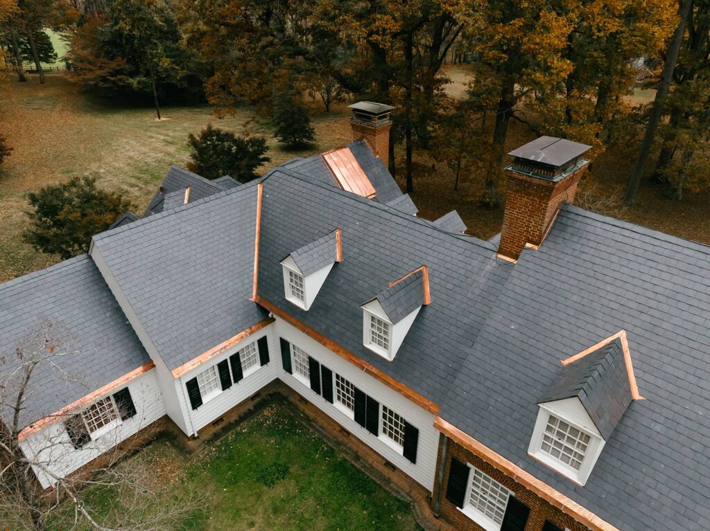 Black slate roof on white cottage home from above with copper accents