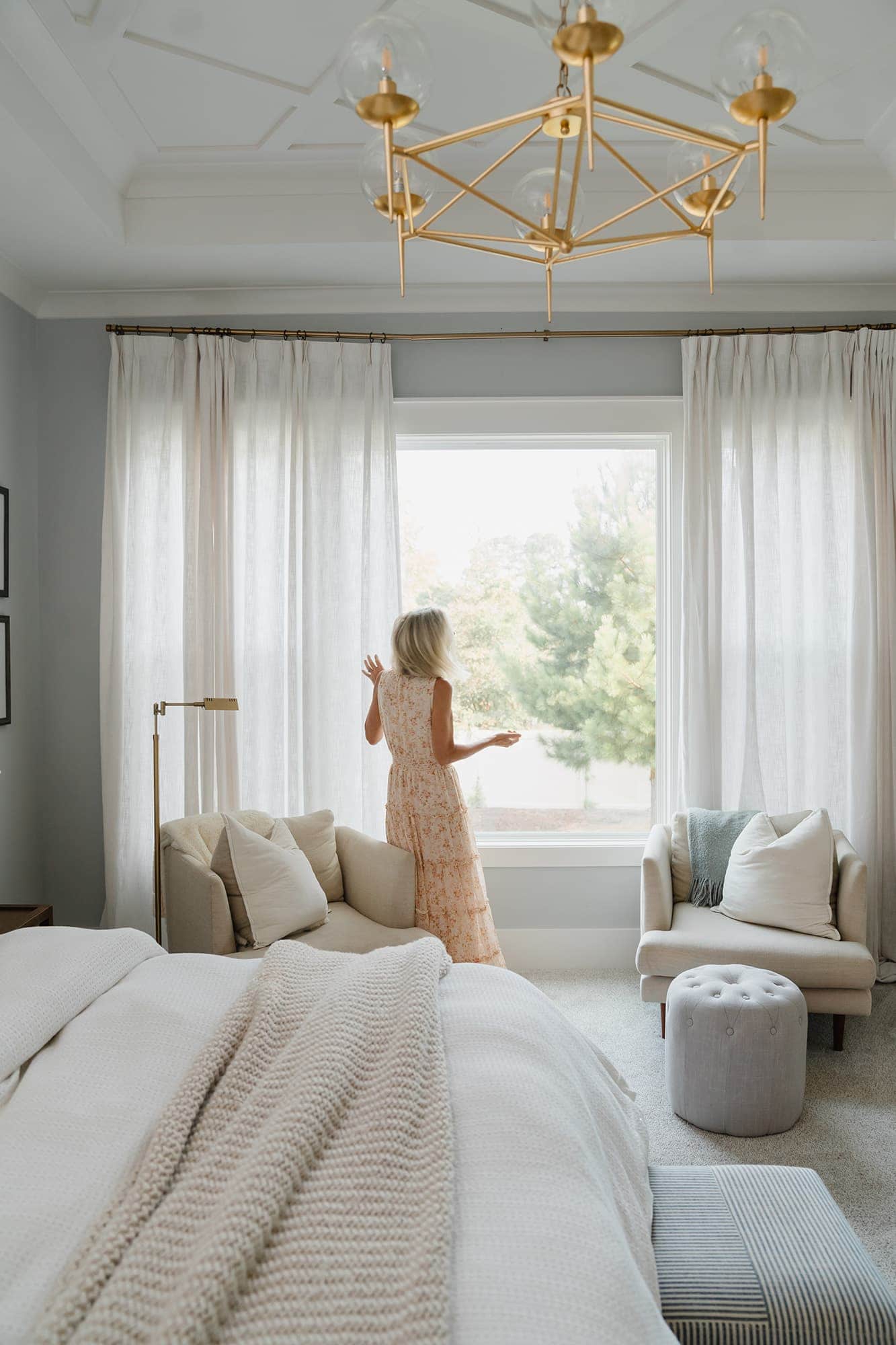 Decorative image of woman fixing drapes at window