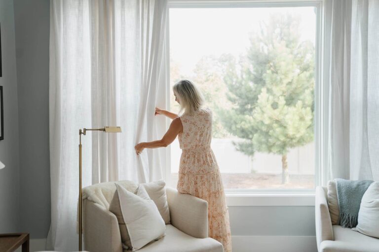 Decorative image of woman fixing drapes at window