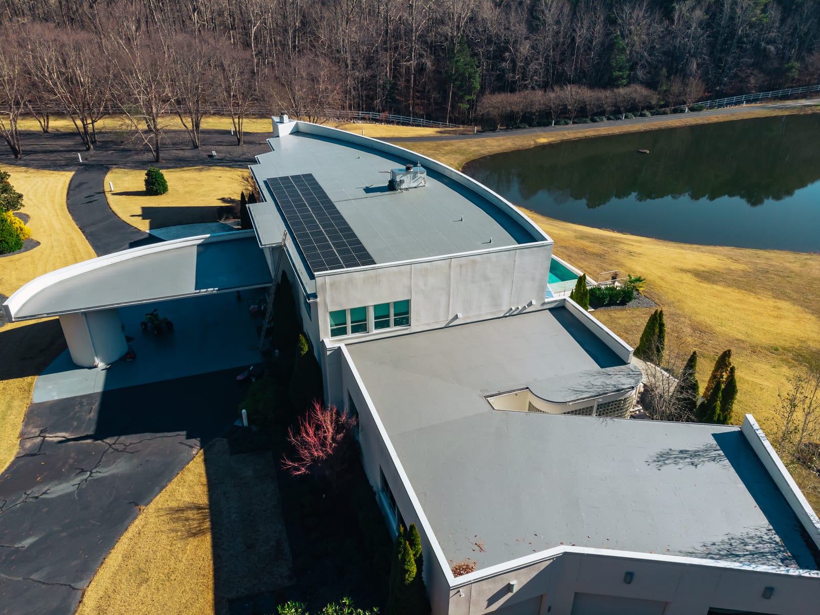Two low-slope membrane roof sections with parapet walls on a white modern home