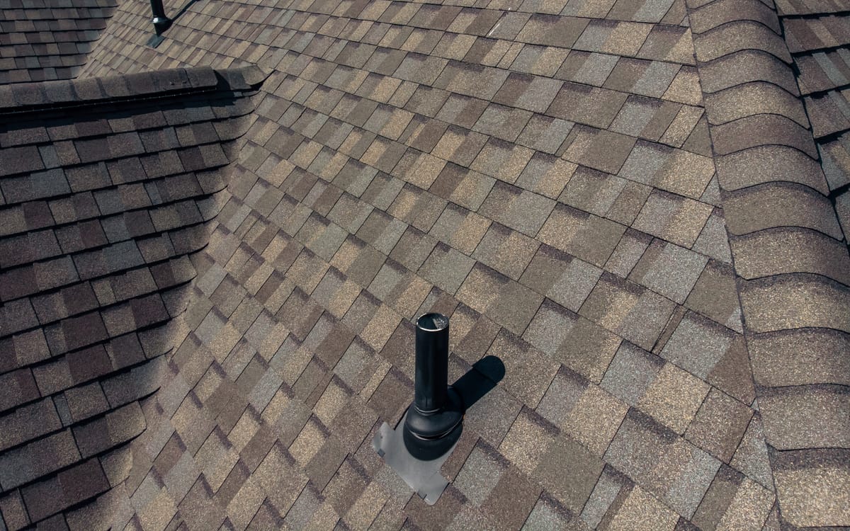 Close-up of new architectural shingles and a sealed pipe boot
