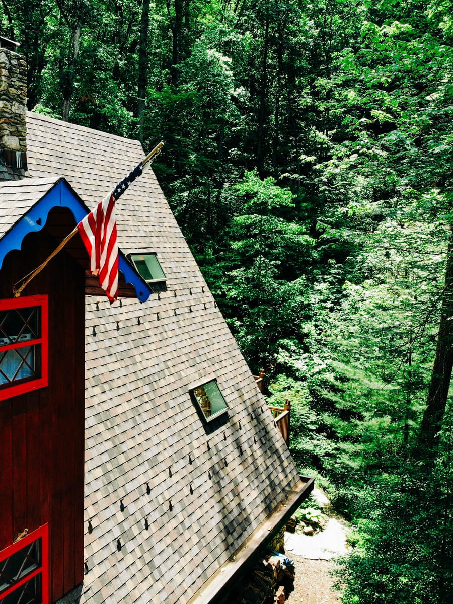 Architectural shingle roof on a mountain cabin with a red dormer and an American flag