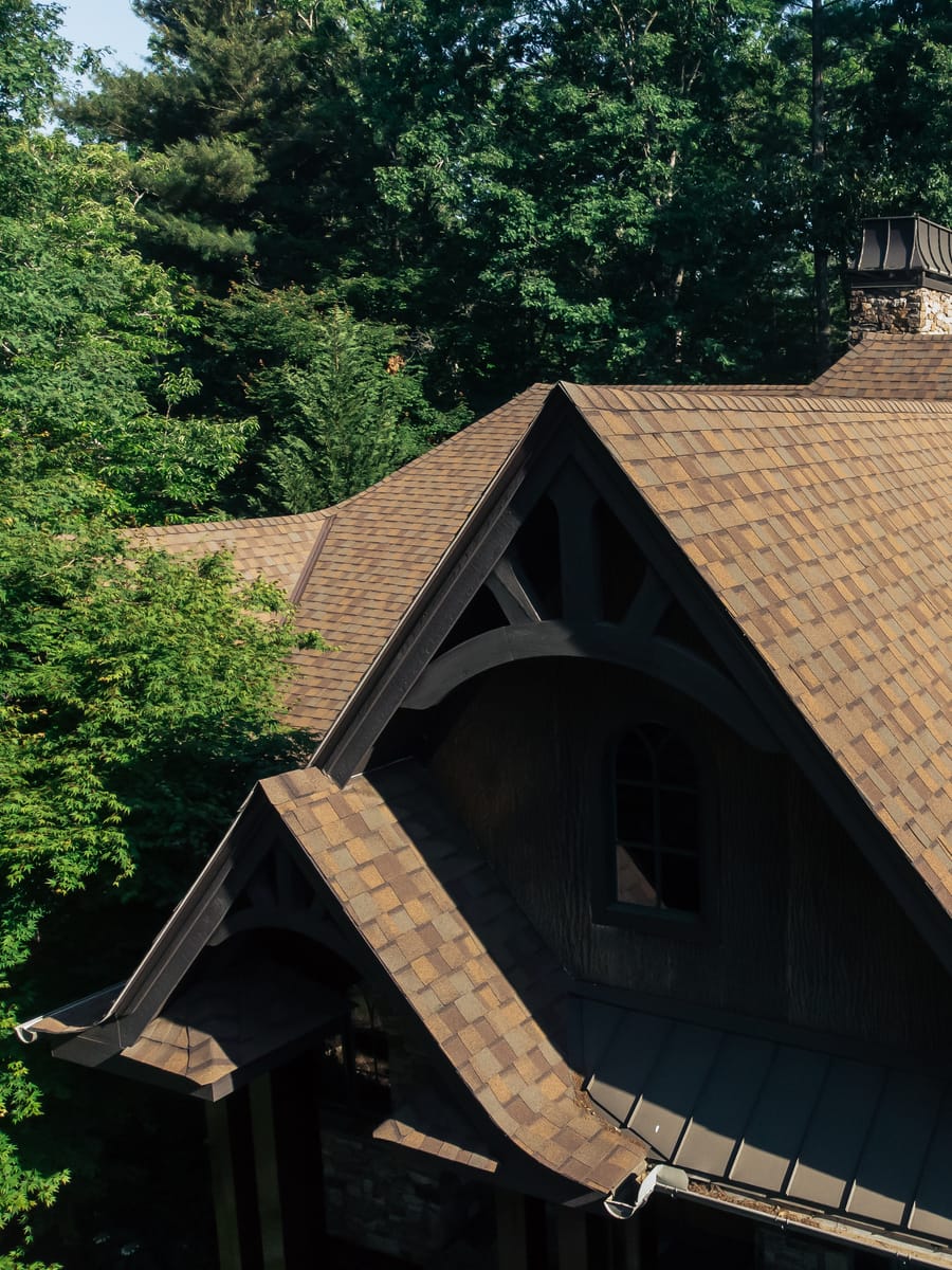 Brown architectural shingles on a craftsman gable with heavy timber brackets