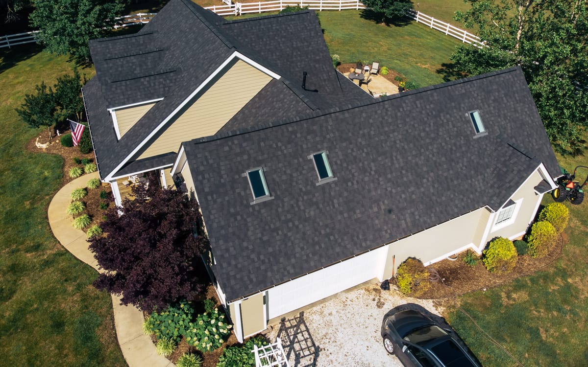 Aerial view of a charcoal shingle roof with skylights on a farm property