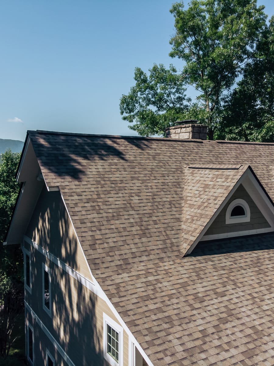 Shingle roof with an eyebrow dormer overlooking a mountain ridgeline