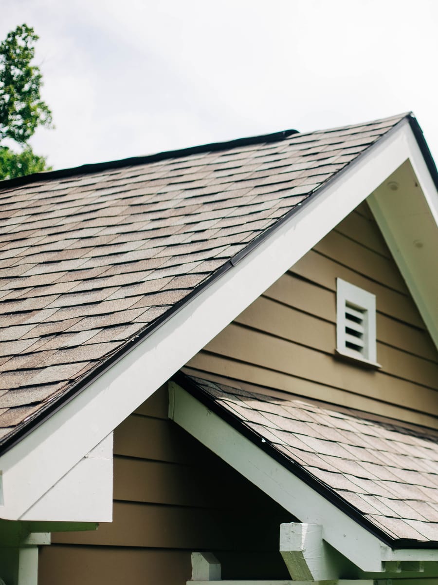 Light architectural shingles on stacked gables of a tan home