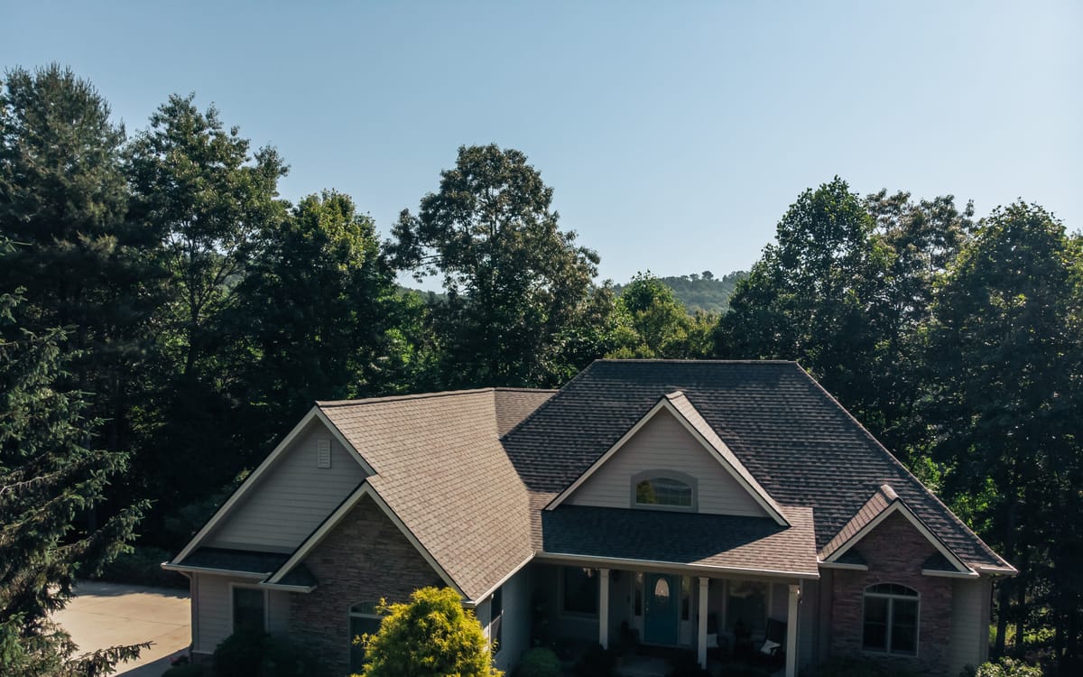 Architectural shingle roof on a stone and siding home with mountains behind it