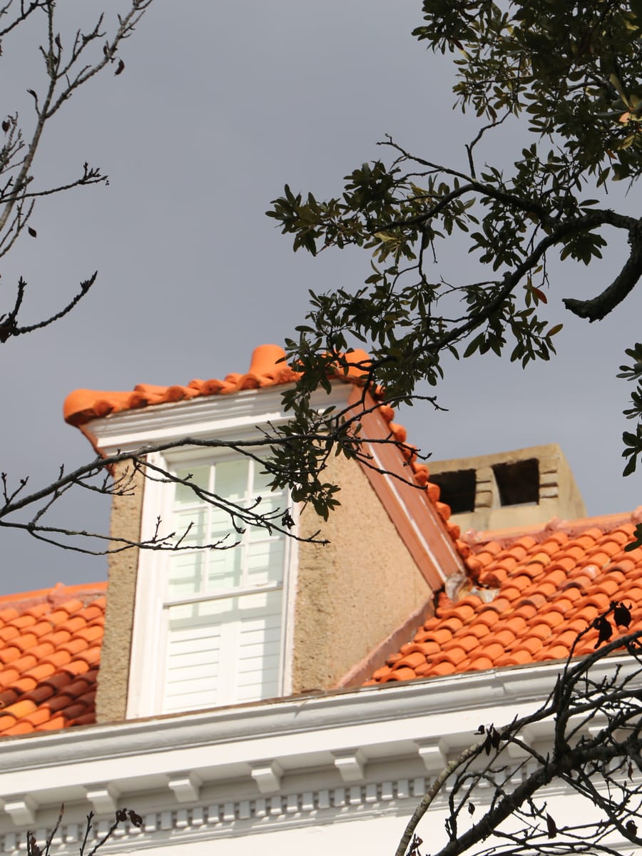 Orange clay tile roof with a copper-capped dormer