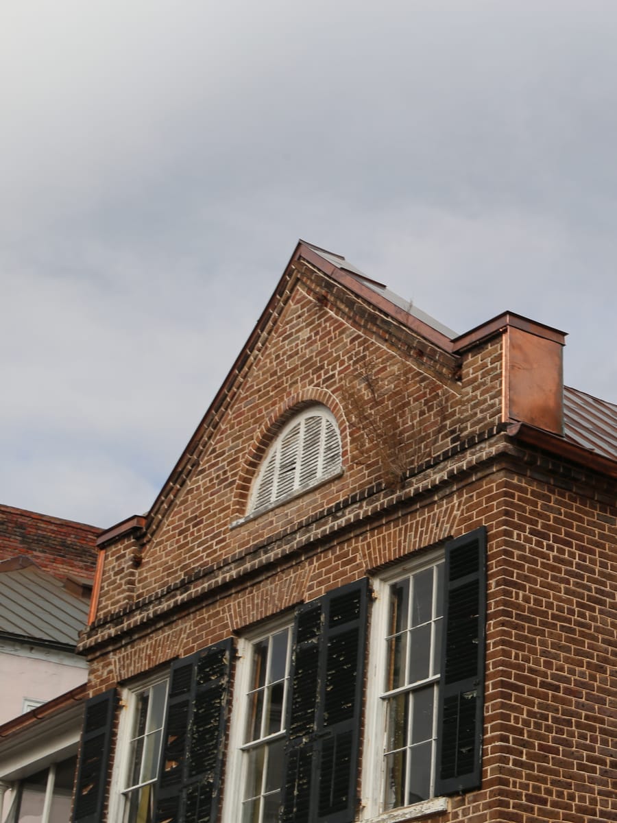 Copper roof on a historic Charleston brick home with a Palladian gable window
