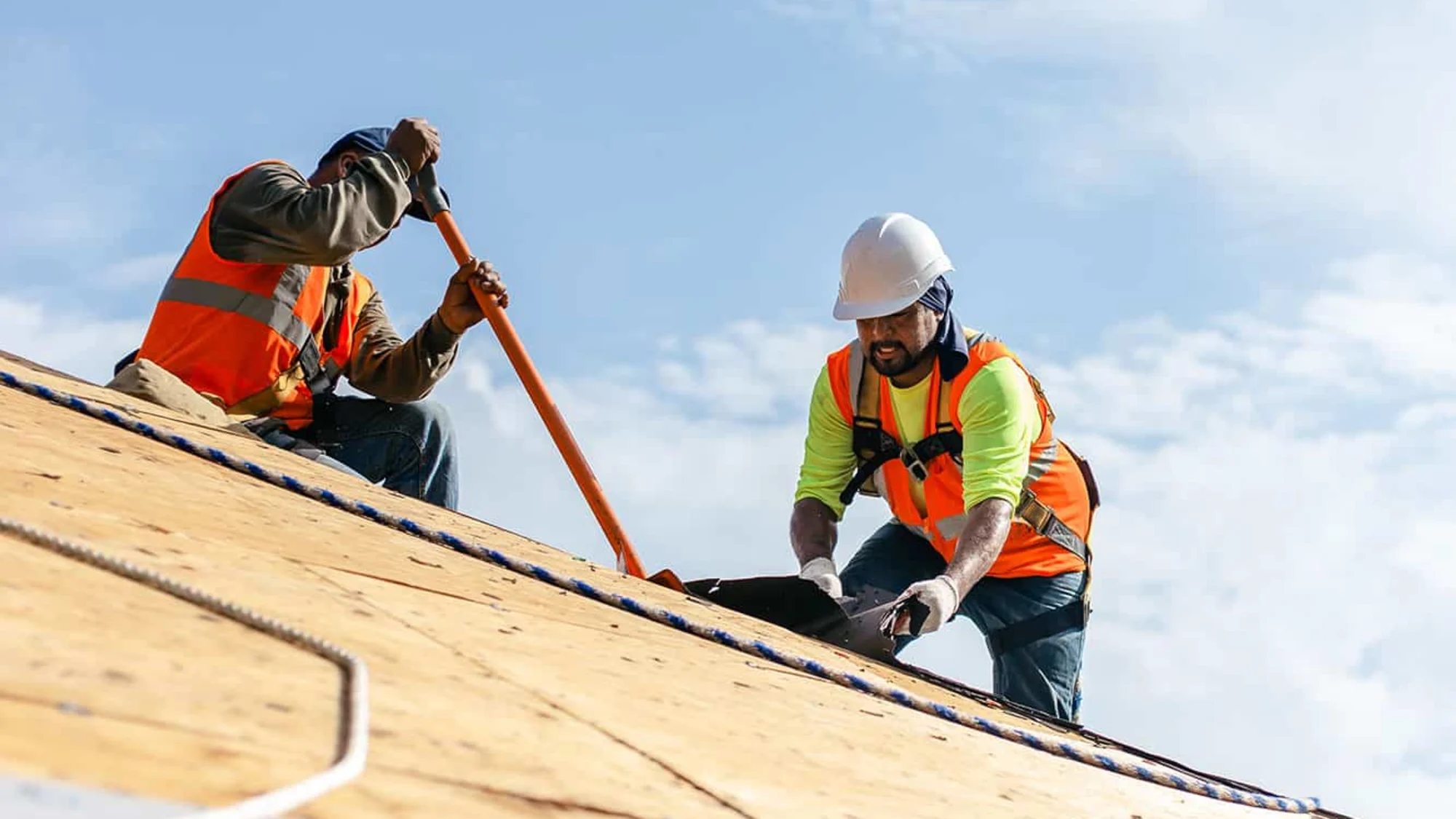 Two Baker Home Exteriors crew members working on a roof deck under open Carolina sky