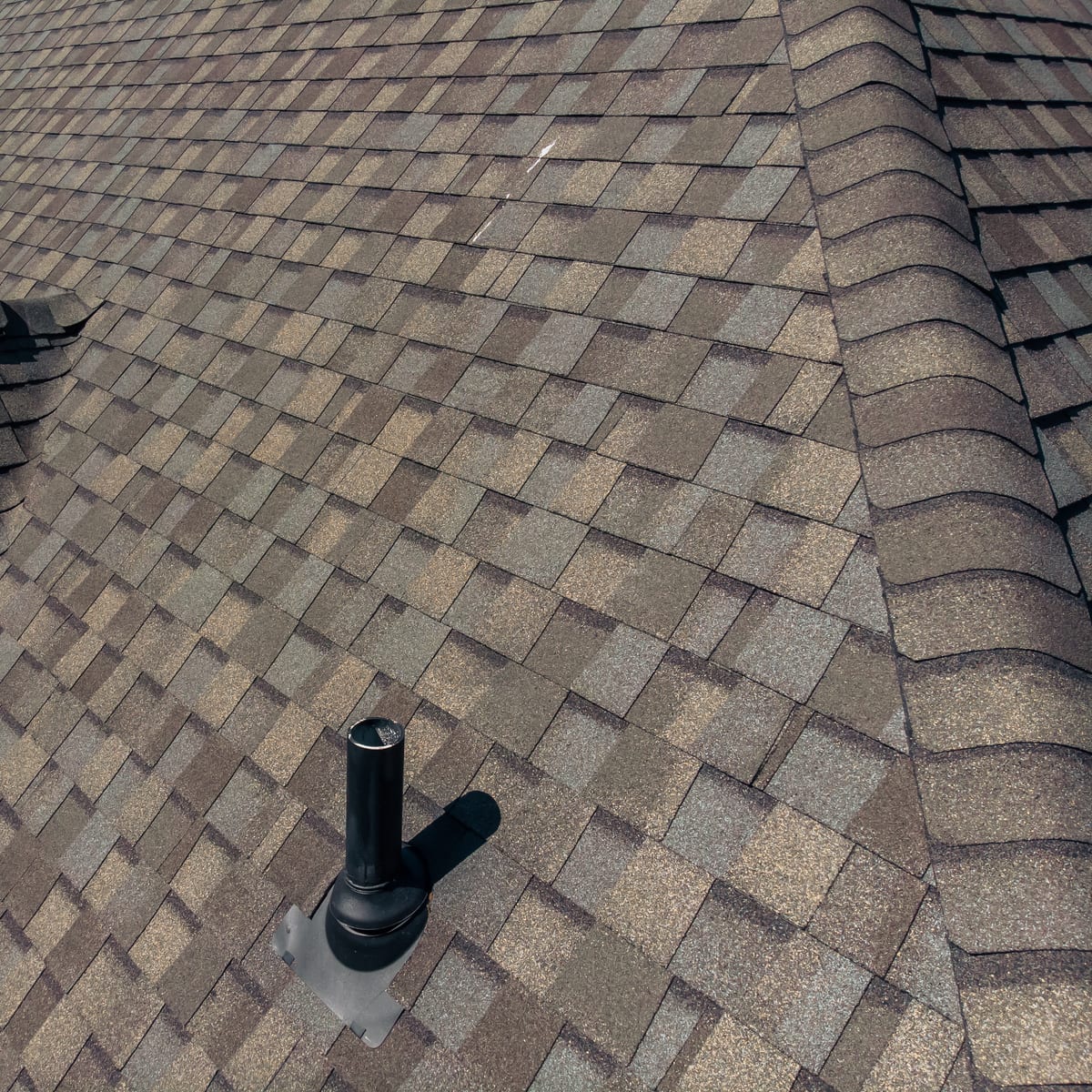 Close-up of new architectural shingles around a sealed pipe boot