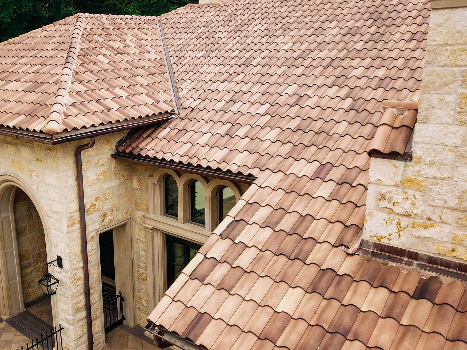 Blended Spanish clay tile roof with copper gutters on a stone Mediterranean-style home