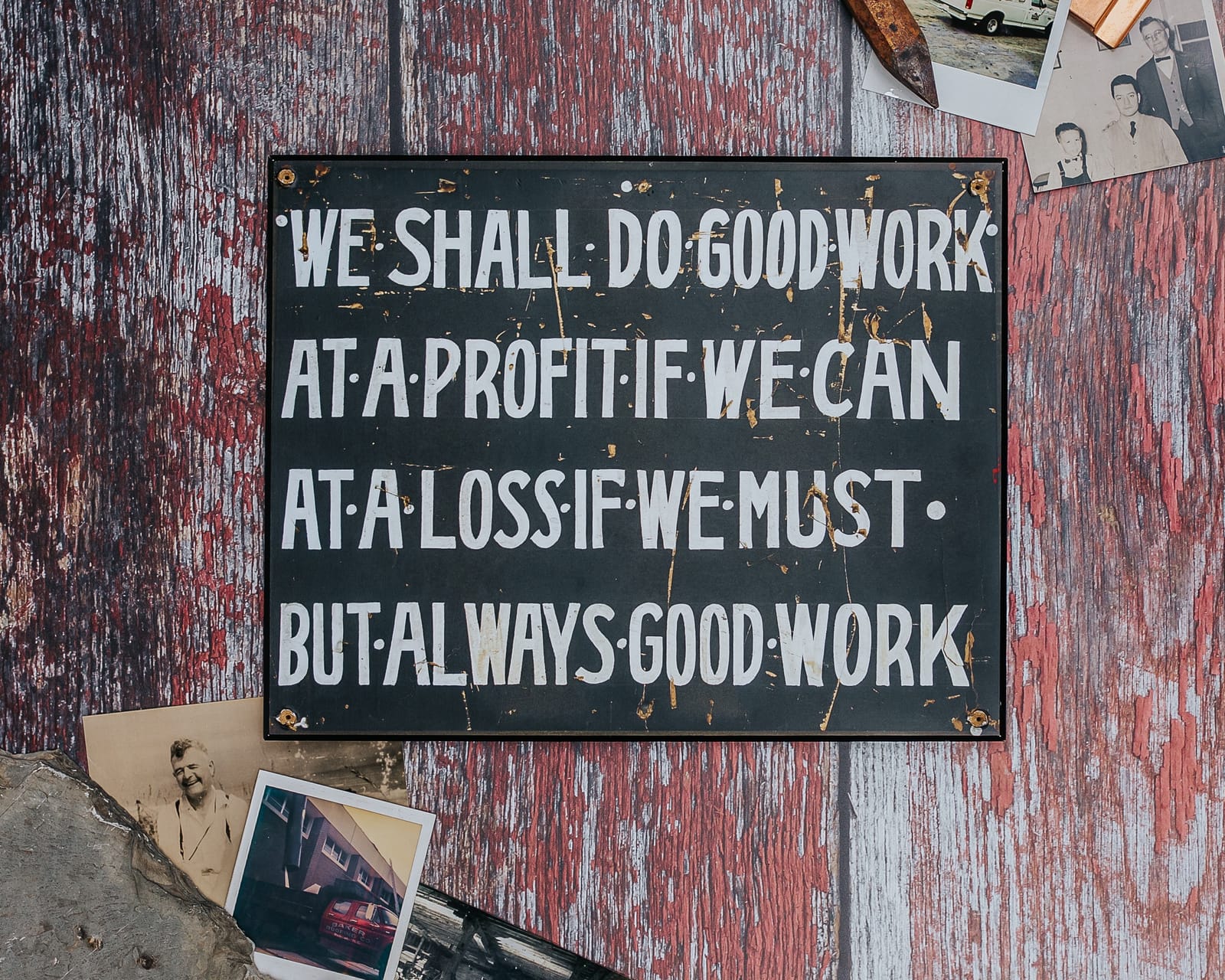 Baker's founding sign, reading We shall do good work, at a profit if we can, at a loss if we must, but always good work, with family photos and old roofing tools
