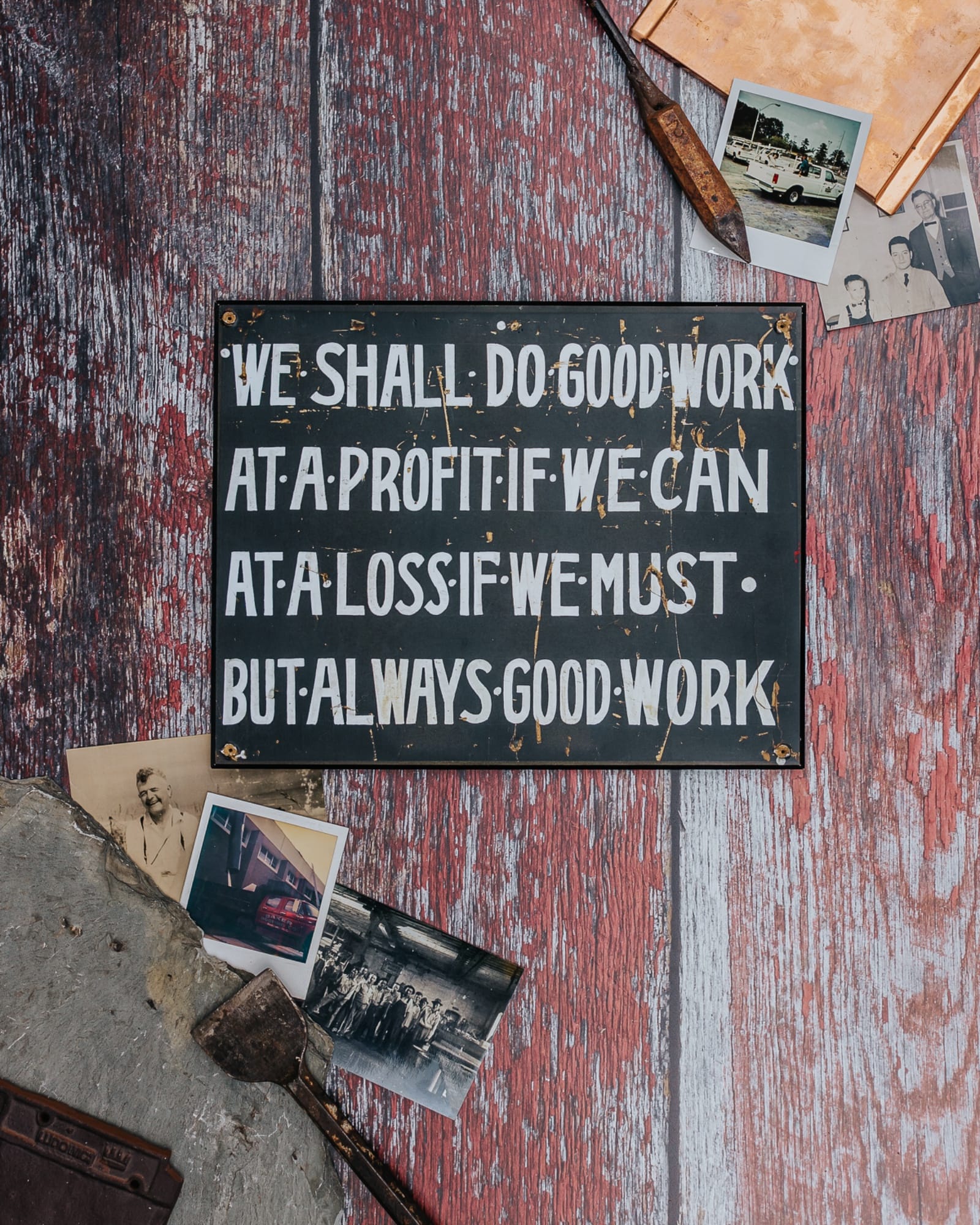 Baker's founding sign, reading We shall do good work, at a profit if we can, at a loss if we must, but always good work, with family photos and old roofing tools