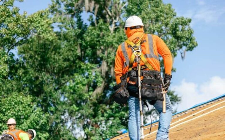 male roofer in safety assessing a shingle roof