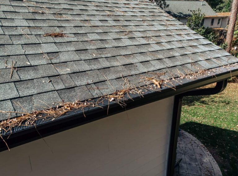 Sticks and leaves piling on gutter guards at corner of home