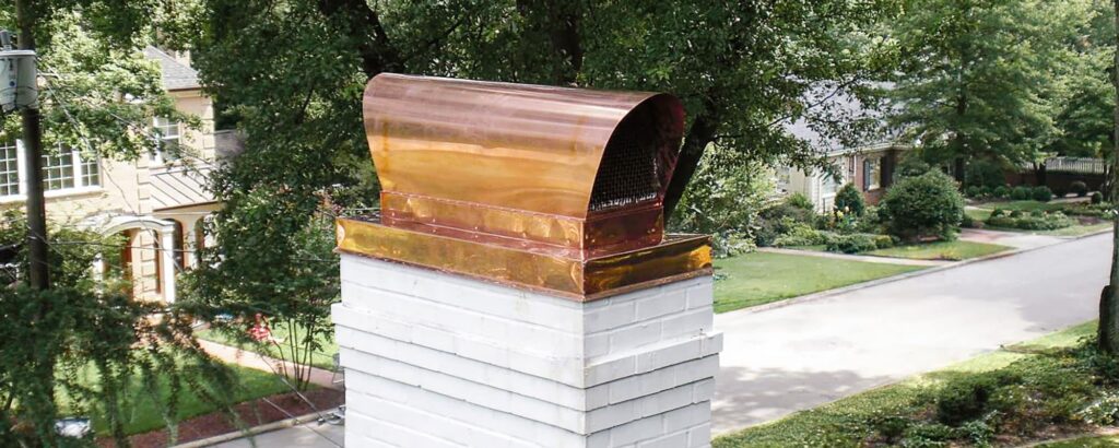 Copper chimney cap on white brick chimney