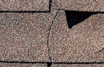 cracked brown shingles on a storm damaged roof