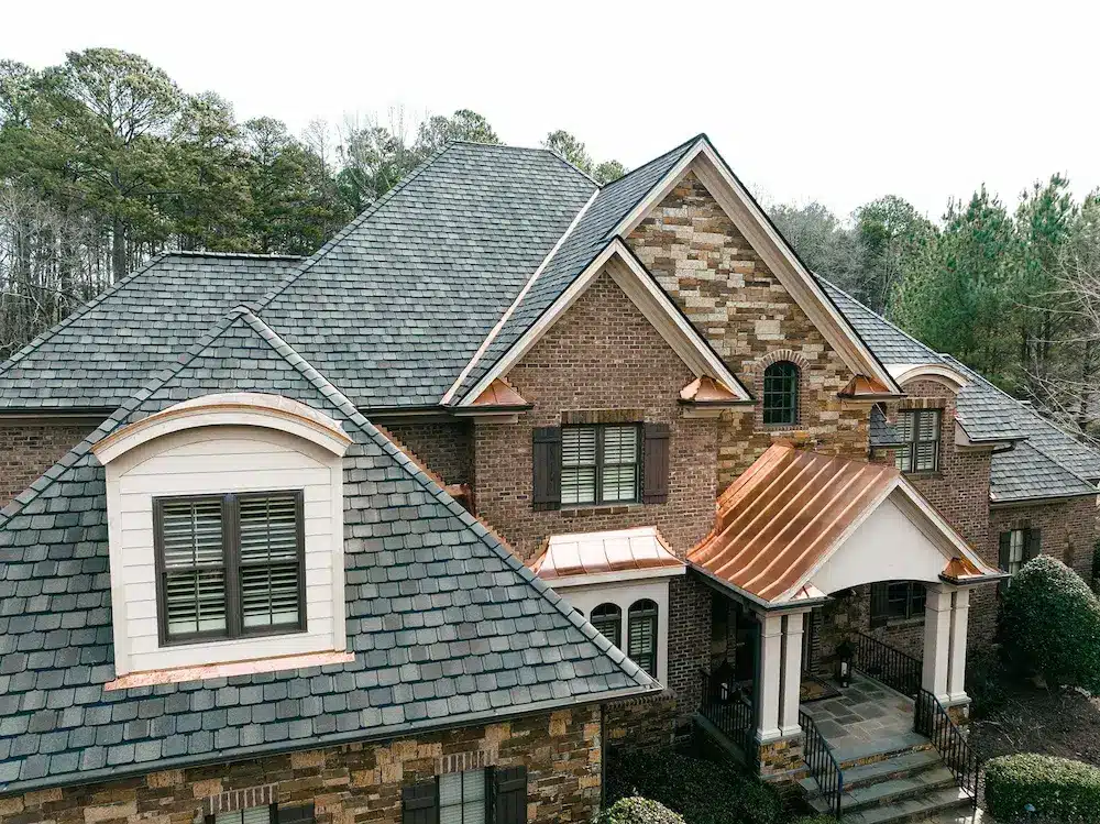 Shingle roof on brick home with copper accents on porch